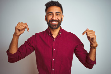 Young indian man wearing red elegant shirt standing over isolated grey background looking confident...