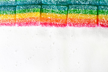 rainbow gummies on a background of white paper sprinkled with sugar, in the upper half of the frame