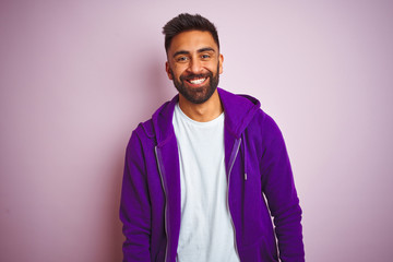 Obraz premium Young indian man wearing purple sweatshirt standing over isolated pink background with a happy and cool smile on face. Lucky person.