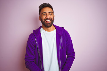 Young indian man wearing purple sweatshirt standing over isolated pink background with ands...