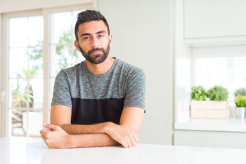 Fototapeta premium Handsome hispanic man wearing casual t-shirt at home with serious expression on face. Simple and natural looking at the camera.