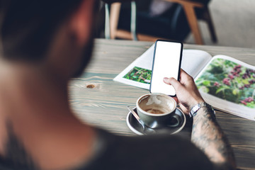 Man use smartphone with white mockup blank screens and reading book with coffee at table in cafe.Communication and technology concept