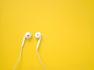White earphones on yellow background. Earphones for listening to music and sound on portable...