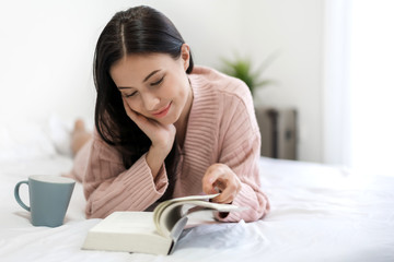 Young woman relaxing and reading book on bed at home