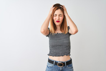 Beautiful redhead woman wearing casual t-shirt standing over isolated white background suffering from headache desperate and stressed because pain and migraine. Hands on head.