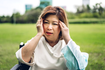 Senior adult elderly asia women serious depressed and feeling headache, thinking of problems at park