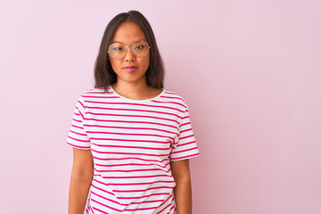 Obraz premium Young chinese woman wearing striped t-shirt and glasses over isolated pink background Relaxed with serious expression on face. Simple and natural looking at the camera.