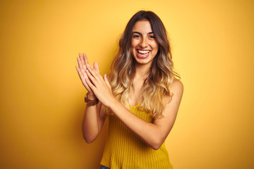 Young beautiful woman wearing t-shirt over yellow isolated background clapping and applauding happy...
