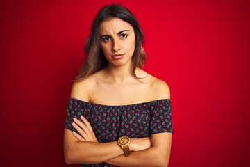 Young beautiful woman wearing a floral t-shirt over red isolated background skeptic and nervous,...