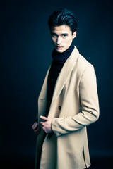 cool real young man in coat on black background posing, lifestyle people concept