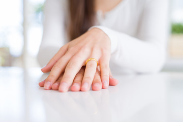 Close up of woman hands wearing wedding alliance ring over white table