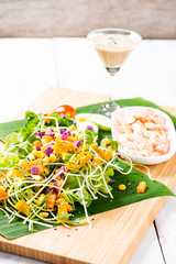 Fresh salad plate with shrimp, salmon, tomato and mixed greens  on wooden background .