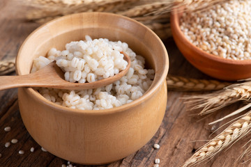 Cooked peeled barley grains in wooden bowl