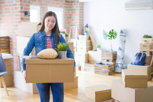 Beautiful asian young woman holding boxes, smiling happy moving to a new home
