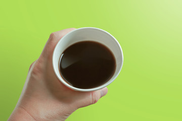 Close-up of a person drinking coffee in a paper cup.  紙コップでコーヒーを飲む人のクローズアップ