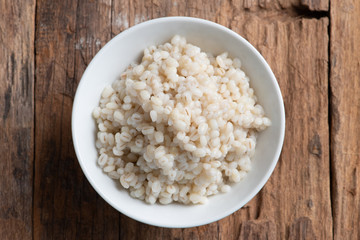 Cooked peeled barley grains in white bowl