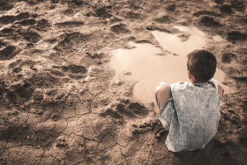 The little boy waiting for drinking water to live through this drought, Concept drought and crisis environment.