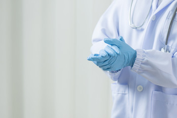 Woman doctor putting blue latex medical gloves on white wall background.Surgeon wearing gloves before surgery at operating room.Risk management protection health care concept.