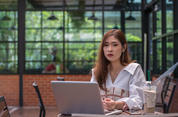 Young businesswoman with a coffee cup working online  on laptop while sitting in coffee shop.