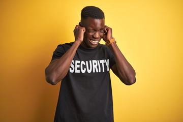African american safeguard man wearing security uniform over isolated yellow background covering...