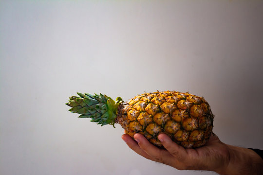 A man holding a pineapple is his hand.