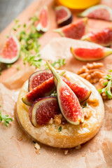 Baked camembert cheese with figs, walnuts, honey and thyme on the rustc background. Selective focus. Shallow depth of field.