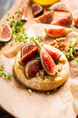 Baked camembert cheese with figs, walnuts, honey and thyme on the rustc background. Selective focus. Shallow depth of field.