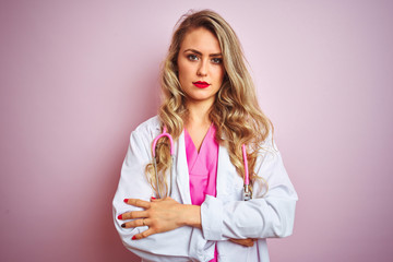 Young beautiful doctor woman using stethoscope over pink isolated background skeptic and nervous,...