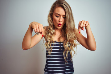 Young beautiful woman wearing stripes t-shirt standing over white isolated background Pointing down with fingers showing advertisement, surprised face and open mouth