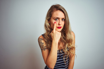 Young beautiful woman wearing stripes t-shirt standing over white isolated background Pointing to the eye watching you gesture, suspicious expression