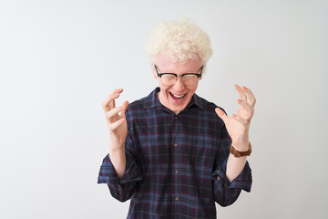 Young albino blond man wearing casual shirt and glasses over isolated white background celebrating mad and crazy for success with arms raised and closed eyes screaming excited. Winner concept