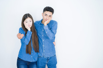 Beautiful young asian couple over white isolated background thinking looking tired and bored with depression problems with crossed arms.