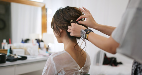 Hairdresser creating a hairstyle for female model in salon