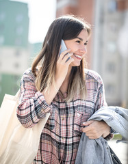 Young girl walking down the street with eco bag and talking on the phone