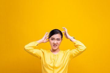 Woman scratching her head isolated over yellow background