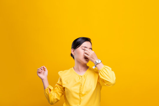 Woman has eyes pain isolated over yellow background