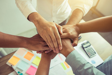 Close up of group of business people joining their hands together in unity.