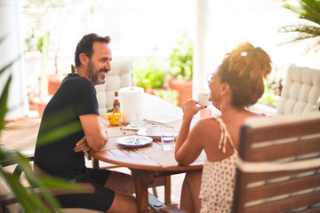 Middle age beautiful couple sitting on terrace drinking cup of coffe