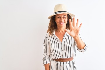 Obraz na płótnie Canvas Middle age businesswoman wearing striped dress and hat over isolated white background showing and pointing up with fingers number five while smiling confident and happy.