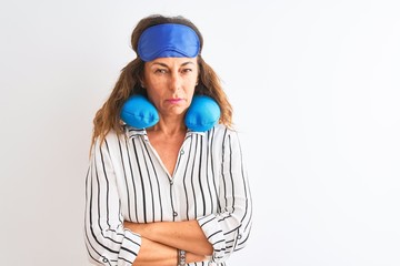 Middle age tourist woman wearing neckpillow and sleep mask over isolated white background skeptic and nervous, disapproving expression on face with crossed arms. Negative person.
