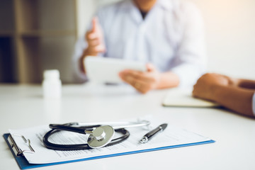 Close up stethoscope and doctor talking the patient at clinic while using the tablet explaining the patient condition and the treatment result.