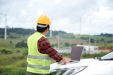 Engineers work by laptop computers at the wind energy field and the renewable energy concept of the electric power industry.