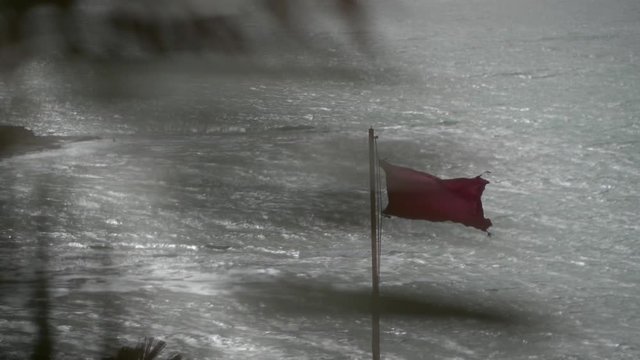beach with red flag and waves