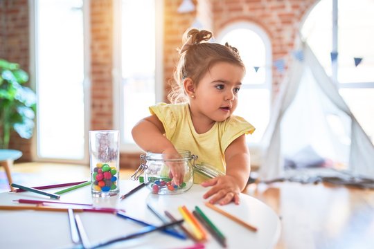 Beautiful toddler standing playing with chocolate colored balls on the table at kindergarten