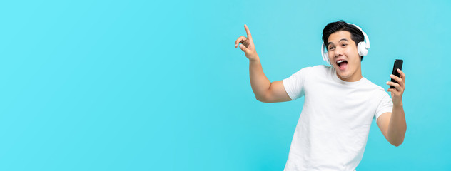 Happy Asian man wearing headphones listening to music from smartphone