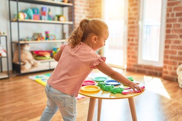 Beautiful blond toddler girl playing  meals using plastic food at kindergarten