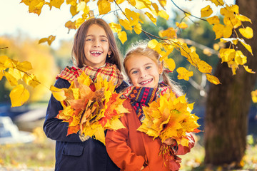 Two cute smiling 8 years old girls posing together in a park on a sunny autumn day. Friendship concept.