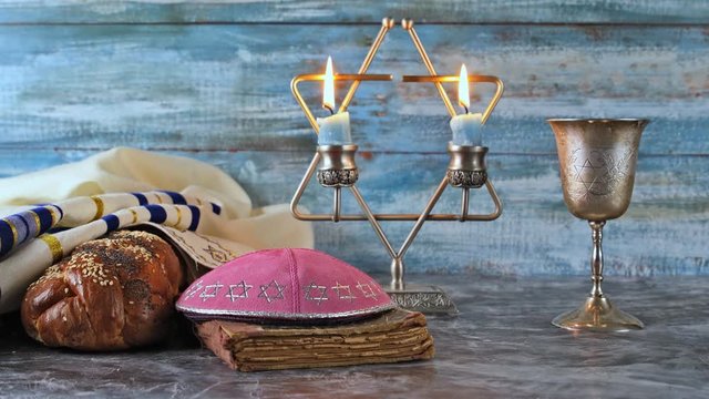 Shabbat eve table with covered challah bread, candles and cup of wine.