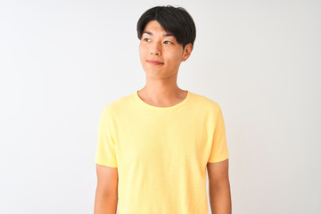 Obraz premium Chinese man wearing yellow casual t-shirt standing over isolated white background smiling looking to the side and staring away thinking.