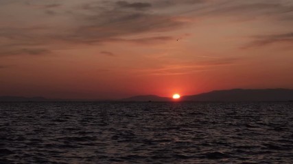 Time lapse of a quiet island at sunset. It shows fluffy clouds moving slowly towards the fading sun. 